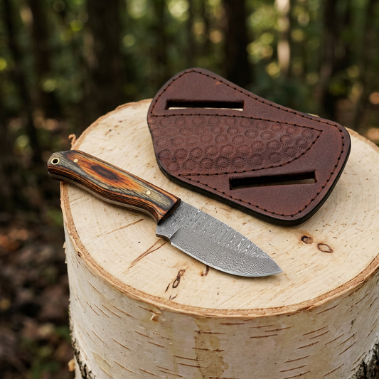 Mini Damascus fixed blade knife and floral cow leather sheath on a woodland stump
