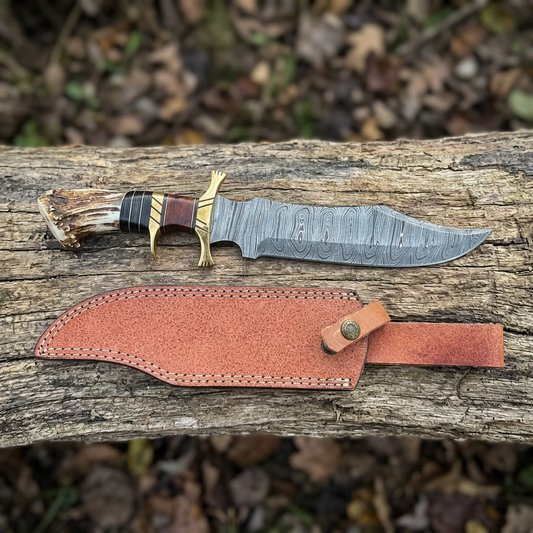 Hand-forged Damascus Bowie knife and cow leather sheath on outdoor timber
