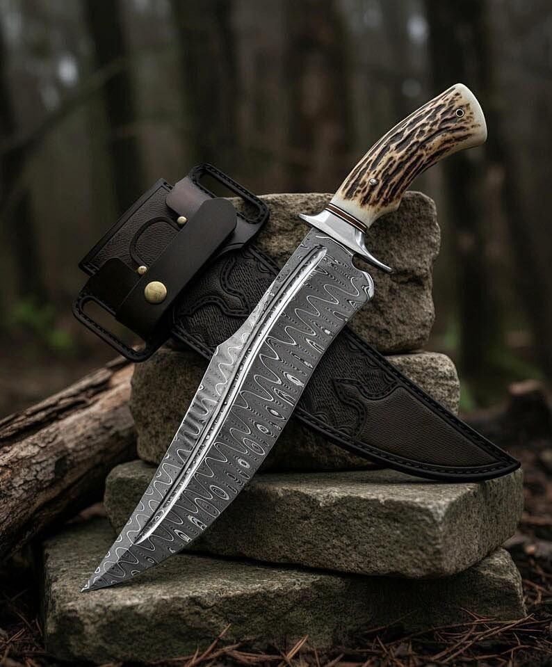 Handmade Damascus steel Bowie knife with stag horn handle and black leather sheath on forest rocks