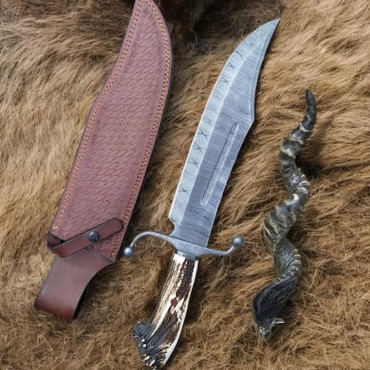 Handmade Damascus steel Bowie knife with stag crown handle double crossguard and embossed leather sheath on animal fur background