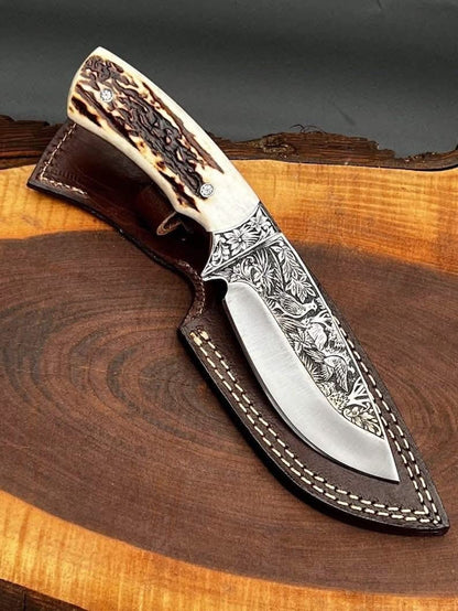 Handmade D2 steel skinner knife with hand engraved eagle and floral blade stag crown handle brass bolster and brown leather sheath on wood slab