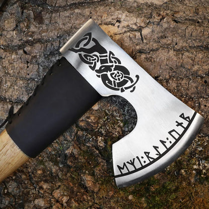 Decorative axe with black handle and engraved design on a wooden background