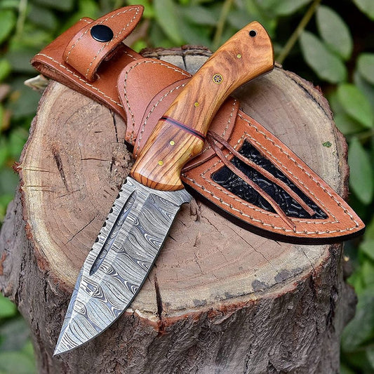 Handmade Damascus steel hunting knife with olive wood and zebrawood handle and embossed brown leather sheath on rustic wood log