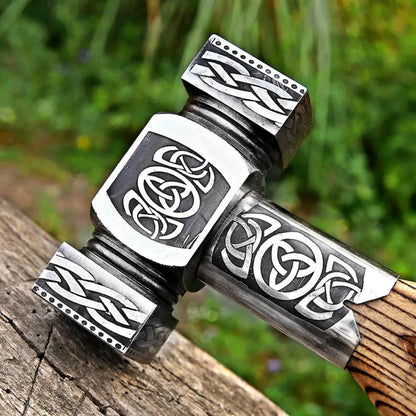 Decorative hammer with Celtic knot designs on a wooden surface
