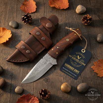 Damascus steel skinner knife walnut handle flat lay on dark rustic wood with HS Knives Store hang tag attached autumn leaves
