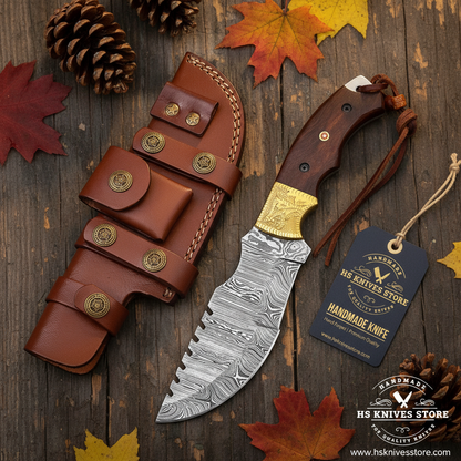 Damascus tracker knife flat lay with brass bolster wood handle and HS Knives Store hang tag on rustic wood with autumn leaves