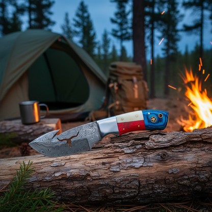 Damascus skinner knife resting on log beside glowing campfire with camping gear in background