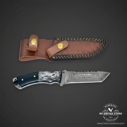 Damascus tanto skinner knife with black micarta bone spacer handle and brown leather sheath on dark charcoal studio background facing right