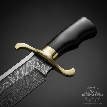 Close-up macro of black hardwood handle and brass S-style curved crossguard on Damascus steel Bowie knife