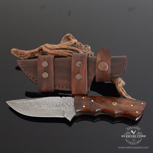 Damascus steel skinner knife walnut handle brass star rivet finger groove dark brown leather sheath dark charcoal studio background