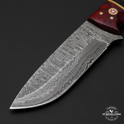 Close-up macro of Damascus steel hunting knife blade showing wavy flowing wave Damascus pattern and polished cutting edge and drop point tip
