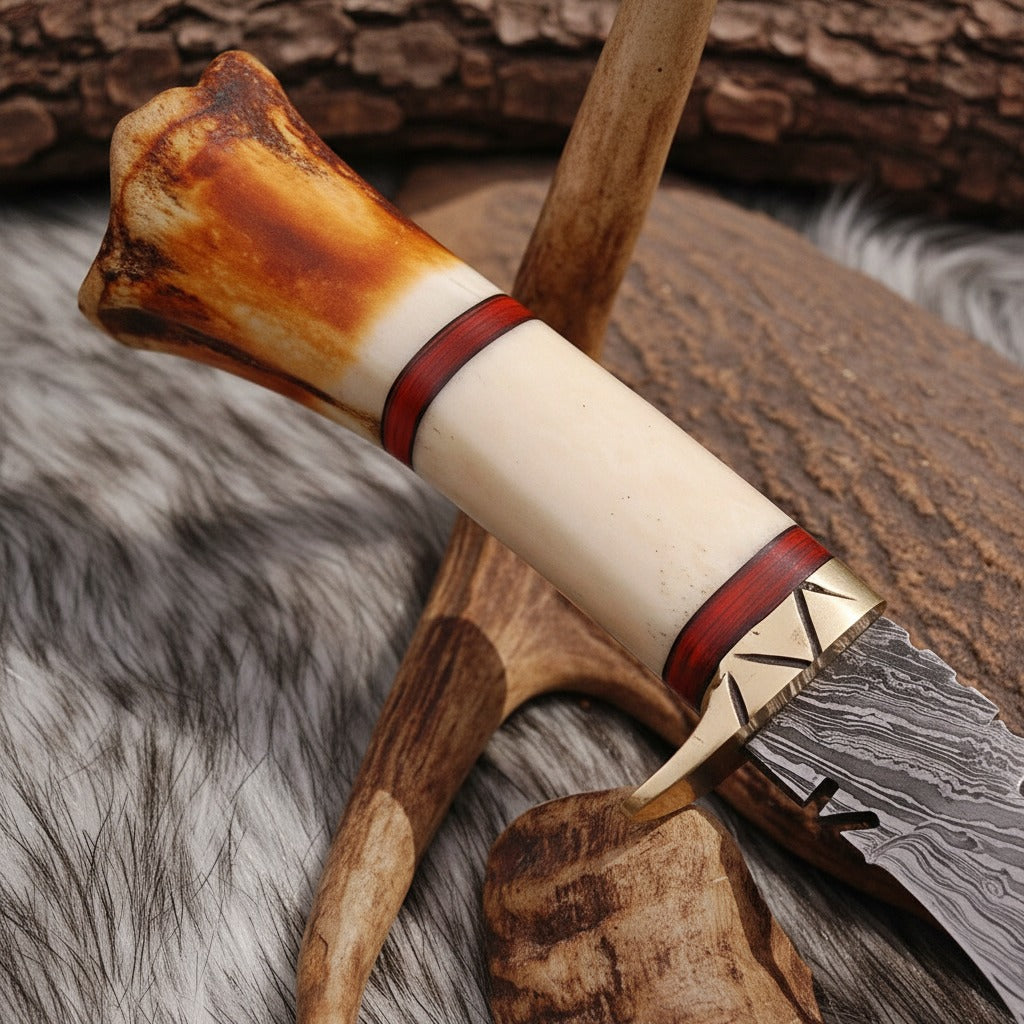A close-up of a handcrafted knife with a bone handle, red leather bands, and a patterned steel blade, resting on a rustic background of wood and fur.
