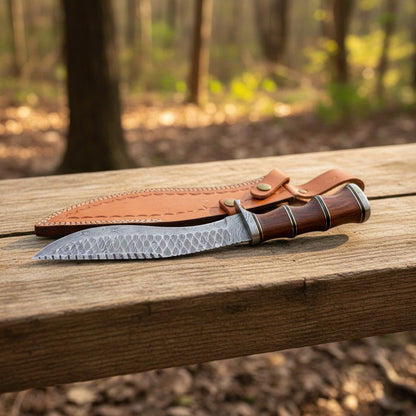  fixed-blade knife with a patterned steel blade, dark wood handle, and brown leather sheath, resting on a wooden bench in an outdoor forest setting.