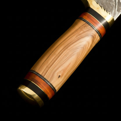  close-up of a knife handle with a light brown wood grain body, accented by dark brown wood inlays and polished brass-colored metal fittings, shown against a solid black background.