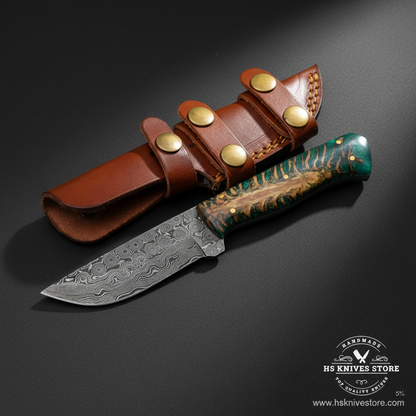 Damascus skinner knife with green resin pine cone handle and tan leather belt sheath mirror view on dark charcoal background