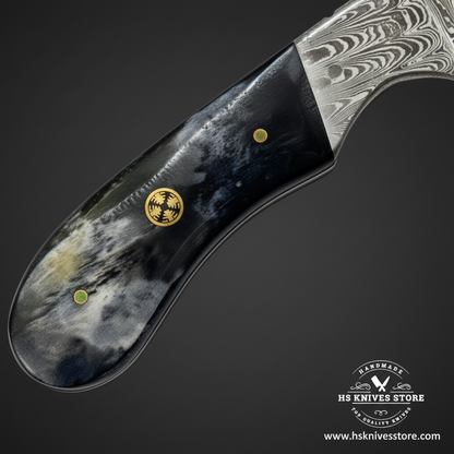 Macro view of natural bone handle with brass mosaic pin and green dot pin and finger groove on Damascus gut hook knife