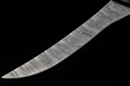 Close up macro shot of Damascus steel fillet knife blade showing layered Damascus pattern with wavy grain and flexible curved blade detail