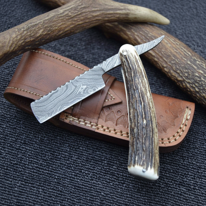 Damascus straight razor with antler handle vertical luxury shot on dark charcoal slate background