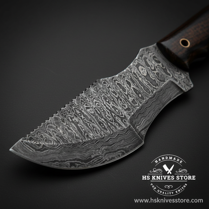Close-up of Damascus steel tracker knife blade showing full coverage layered wavy Damascus pattern and upswept tip