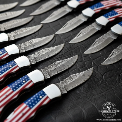 Close-up macro of multiple Damascus steel folding knife blades fanned out showing bold swirling wave Damascus pattern