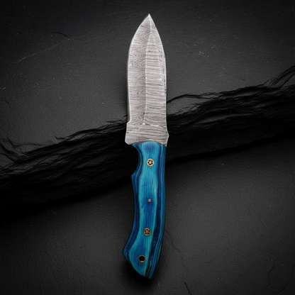 Damascus steel skinner knife with blue pakkawood handle vertical luxury shot on dark charcoal slate background blade pointing up