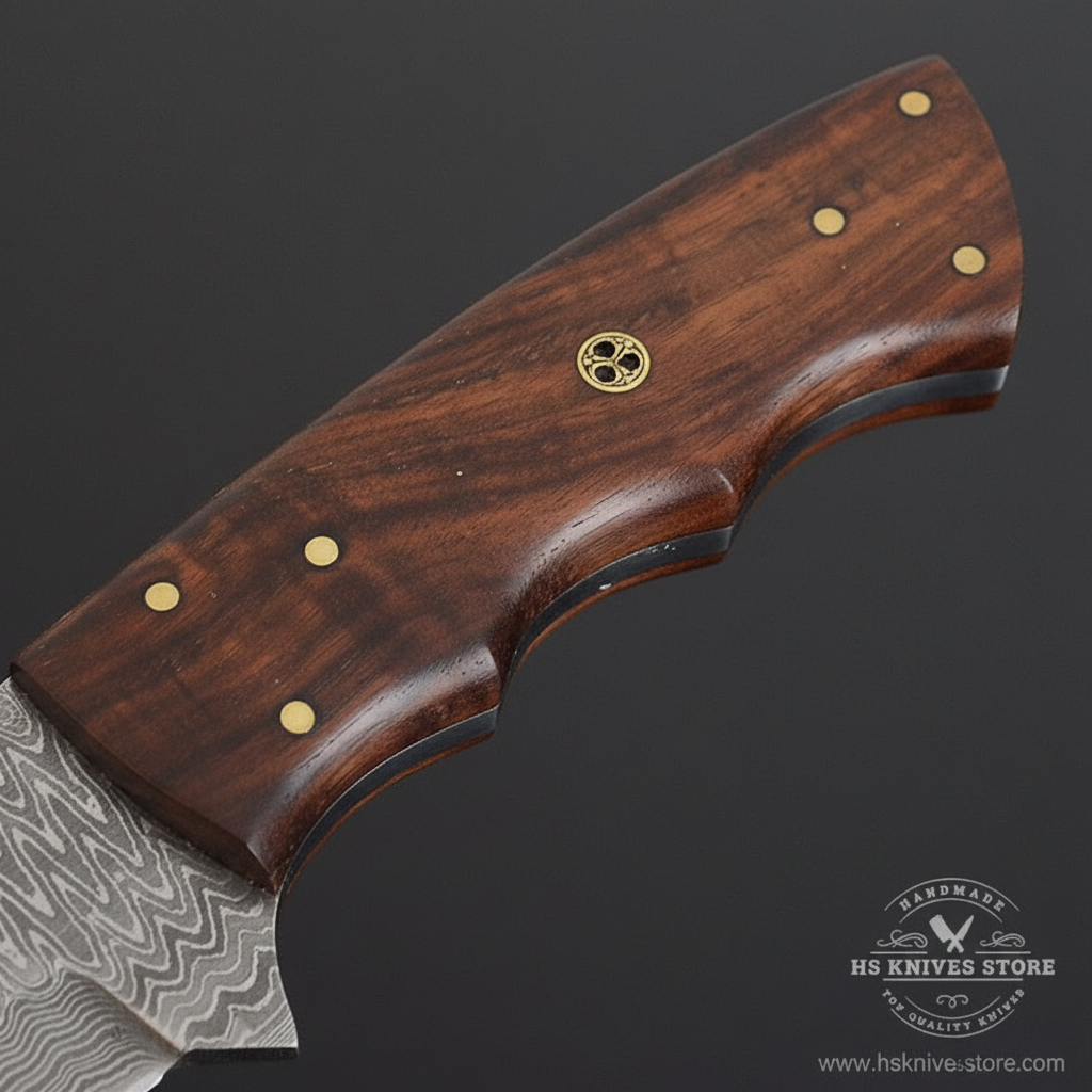 Close-up macro of dark walnut handle with finger groove brass dot rivets and decorative brass star medallion rivet on Damascus skinner knife