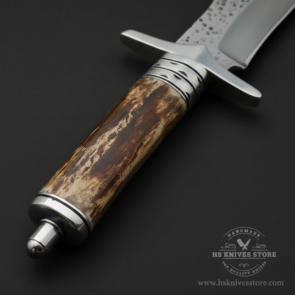 Close-up macro of natural stag antler handle with warm brown tones wire collar and wide silver steel double crossguard on Bowie knife