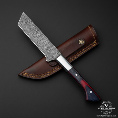 Damascus tanto cleaver knife with blue red pakkawood handle steel bolster and brown leather sheath on dark charcoal studio background facing right