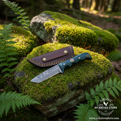 Damascus tanto skinner knife with teal bone handle and burgundy leather sheath on mossy rocks in outdoor forest setting