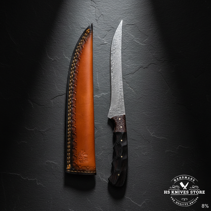 Damascus steel fillet knife displayed vertically on dark slate with ebony honeycomb handle and two-tone leather sheath luxury shot