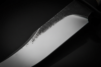 Close up macro shot of 1095 high carbon steel Bowie knife blade showing hand-forged black spine contrasting with mirror polished cutting edge