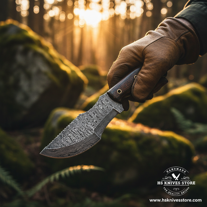 Hand gripping dark brown micarta handle Damascus tracker knife in outdoor forest action shot with golden hour light