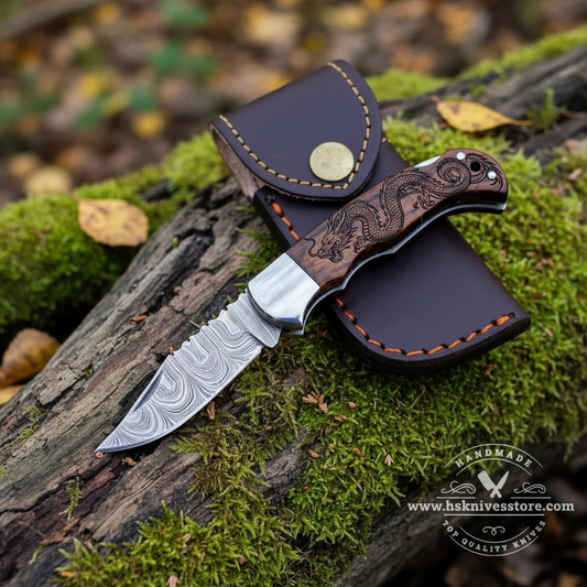 Damascus steel folding pocket knife open blade resting on mossy rocks in outdoor forest setting with dark brown leather sheath