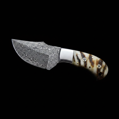 Hand forged raindrop Damascus skinner knife with ram horn handle and steel bolster on black background