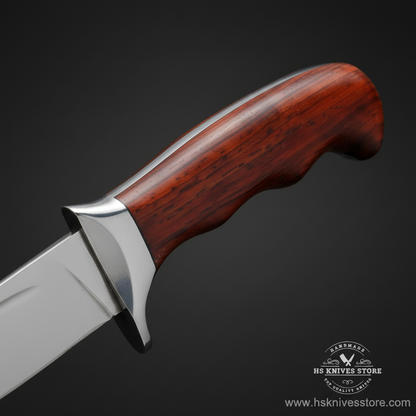 Macro view of dark reddish-brown rosewood handle with smooth contour and integrated silver bolster on J2 steel skinner knife