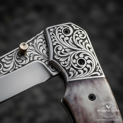 Close-up macro of floral acanthus scroll engraved steel bolster with two black rivets on camel bone handle folding knife