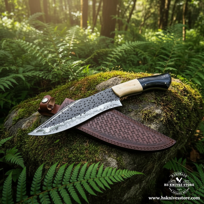 Carbon steel hand-etched Bowie knife with bone horn handle and leather sheath on mossy rocks in forest setting