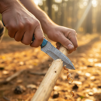 Rugged hands using Damascus steel skinner knife with blue pakkawood handle to carve wooden stick outdoors forest floor golden light wood shavings