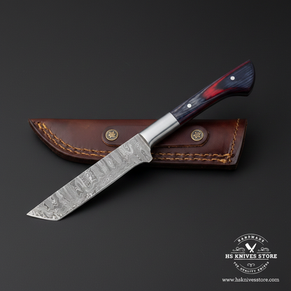 Damascus tanto cleaver knife with blue red pakkawood handle steel bolster and brown leather sheath studio mirror view facing left