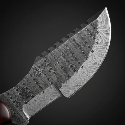 Damascus steel tracker blade close-up showing bold layered pattern and jimping on spine near guard