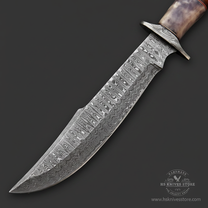 Close-up macro of Damascus steel Bowie blade showing bold swirling ladder Damascus pattern and wide fuller groove and flared butterfly crossguard