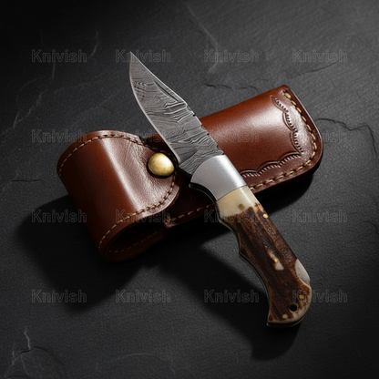 Damascus steel folding knife with stag antler handle vertical luxury shot on dark charcoal slate background