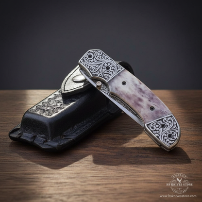Camel bone handle folding knife closed showing full handle floral engraved bolsters and black leather sheath dark charcoal studio
