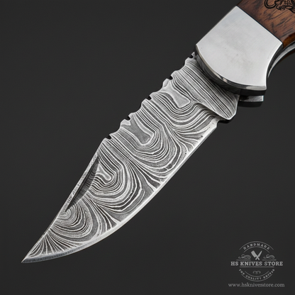 Close-up macro of Damascus steel folding blade showing bold flowing wave ladder Damascus pattern and sharp polished edge