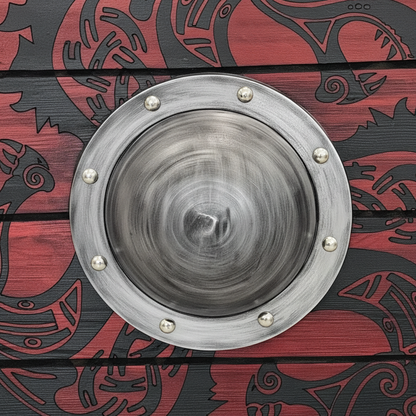Close-up of raised silver center boss, red wood planks, rivets, and dark Norse artwork on a Viking shield
