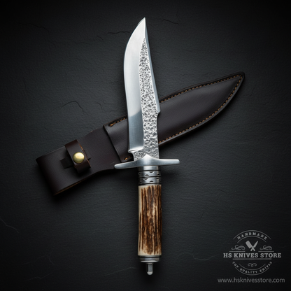 Vertical luxury shot of stag antler handle Bowie knife on dark slate background with dark black leather sheath
