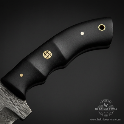 Close-up macro of black micarta handle with matte black surface and ergonomic finger grooves and brass decorative screw pin and lanyard hole
