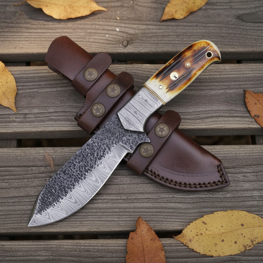 Handmade Damascus tracker knife flat lay on rustic wood with dark leather sheath and star brass conchos