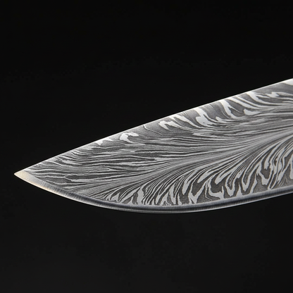 Macro detail of hand-forged Damascus steel blade showing bold feather wing flowing pattern and razor sharp edge on hunting knife