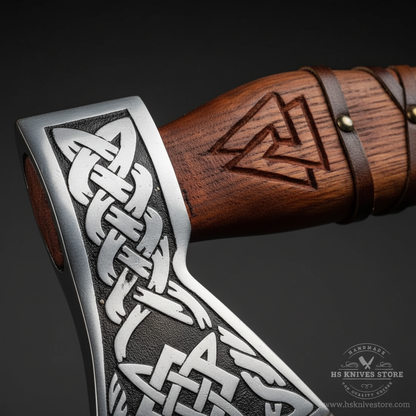 Close-up macro of Viking axe head showing deeply etched Celtic knot interlace pattern and Norse Viking designs on polished silver steel